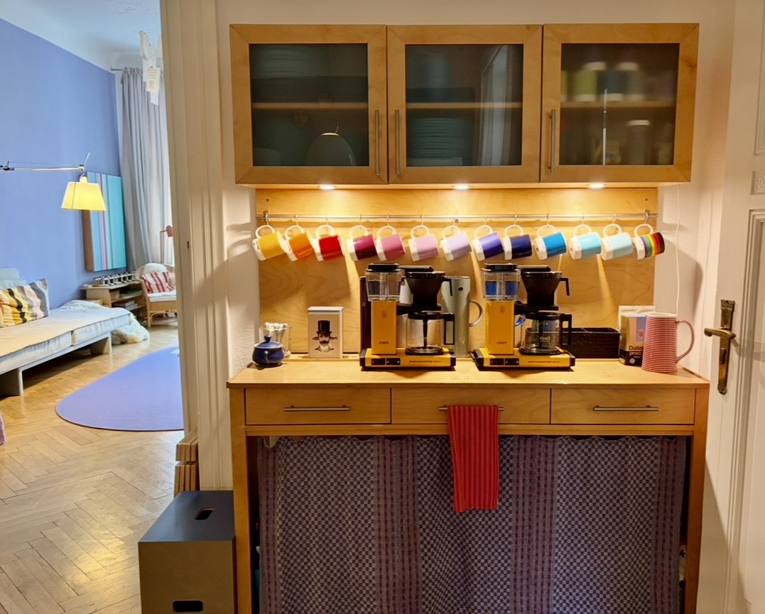 Kaffeestation mit zwei Maschinen und einer Reihe farbiger Tassen